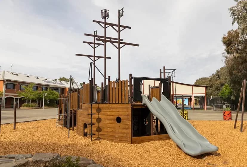 Playground equipment with a slide and loose-fill impact surfacing